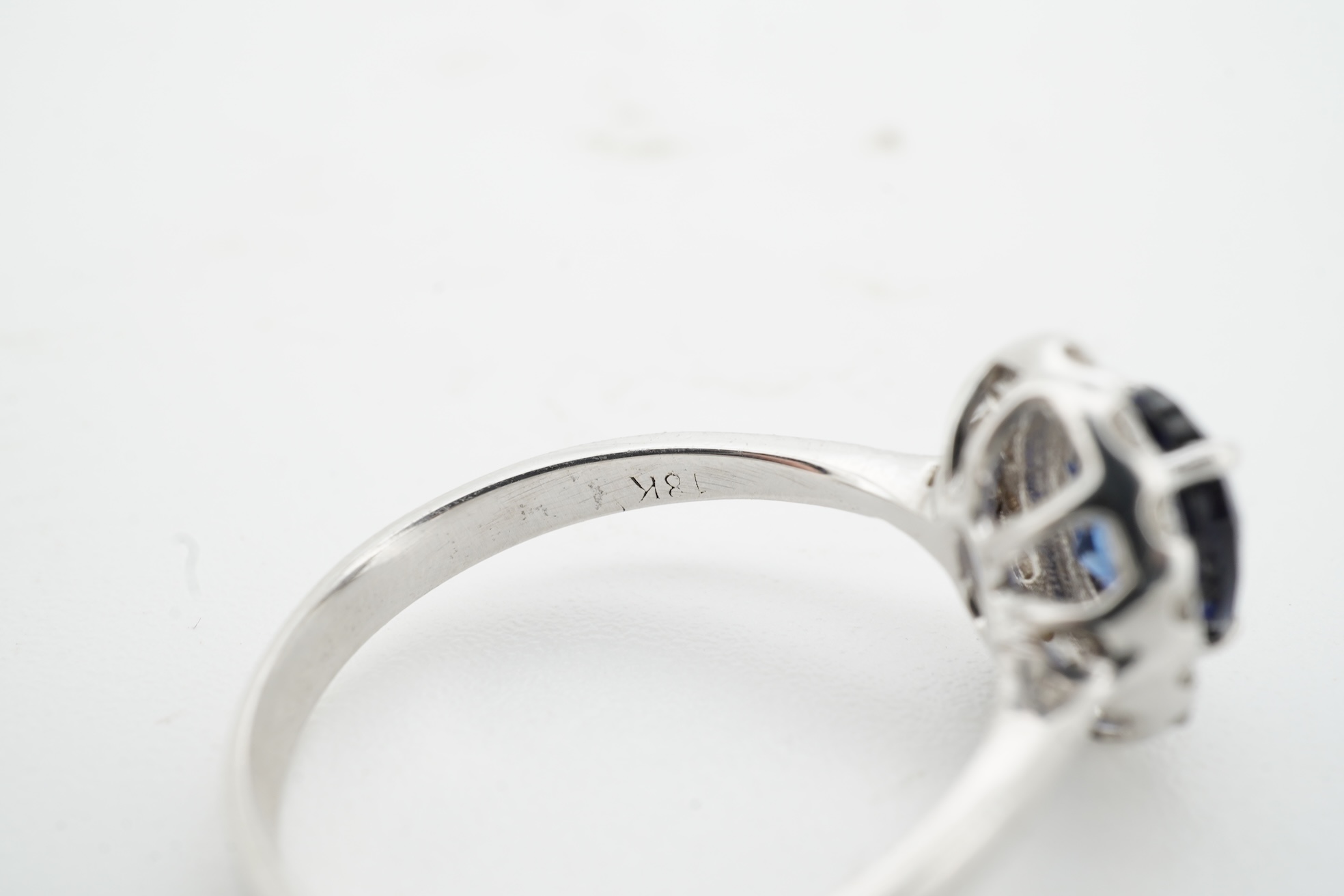 A synthetic sapphire and diamond cluster ring, mounted in white gold, size L1/2, stamped 18K, gross weight approximately 1.5 grams